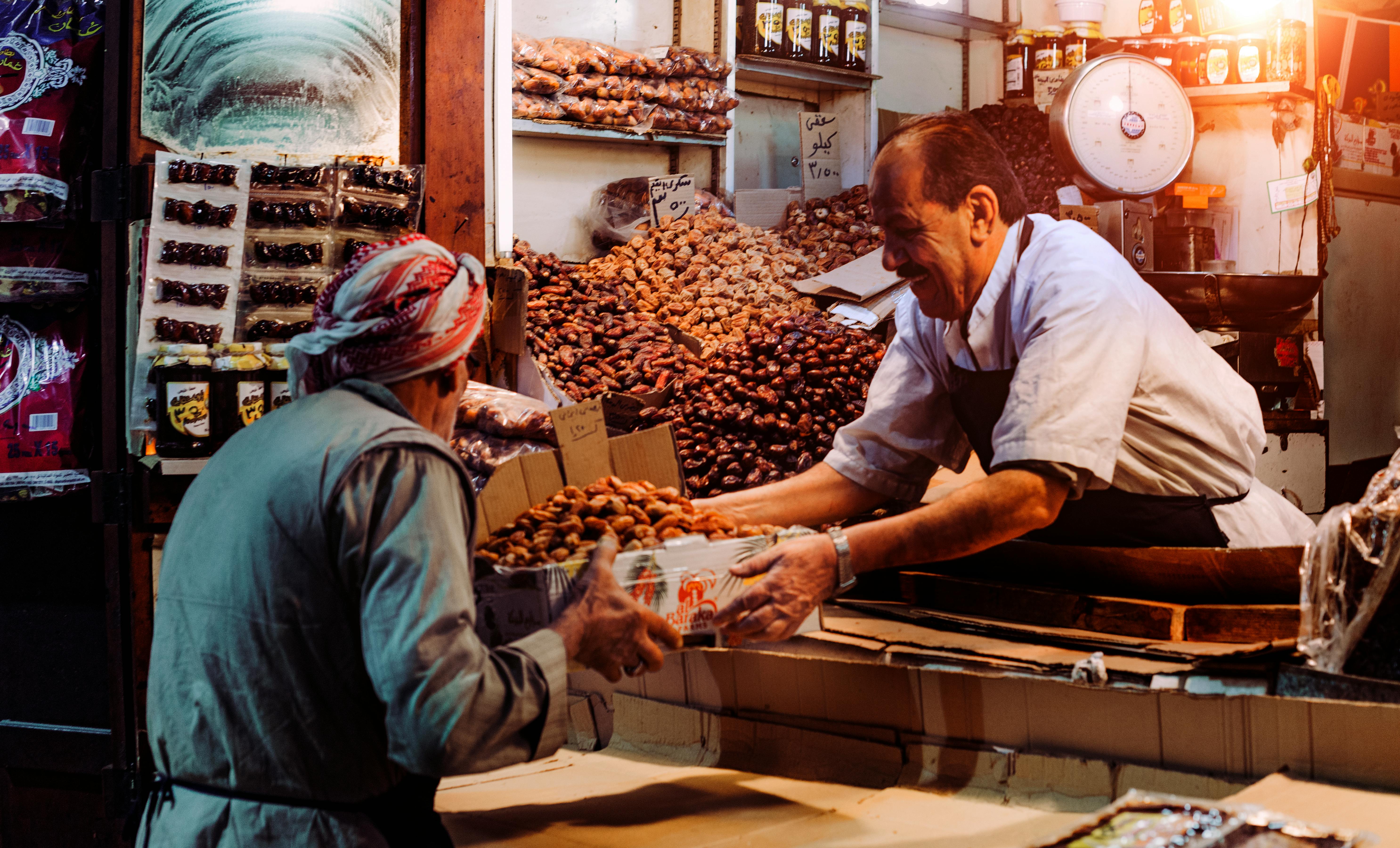 An image of a market stall, where a man is serving another nuts.